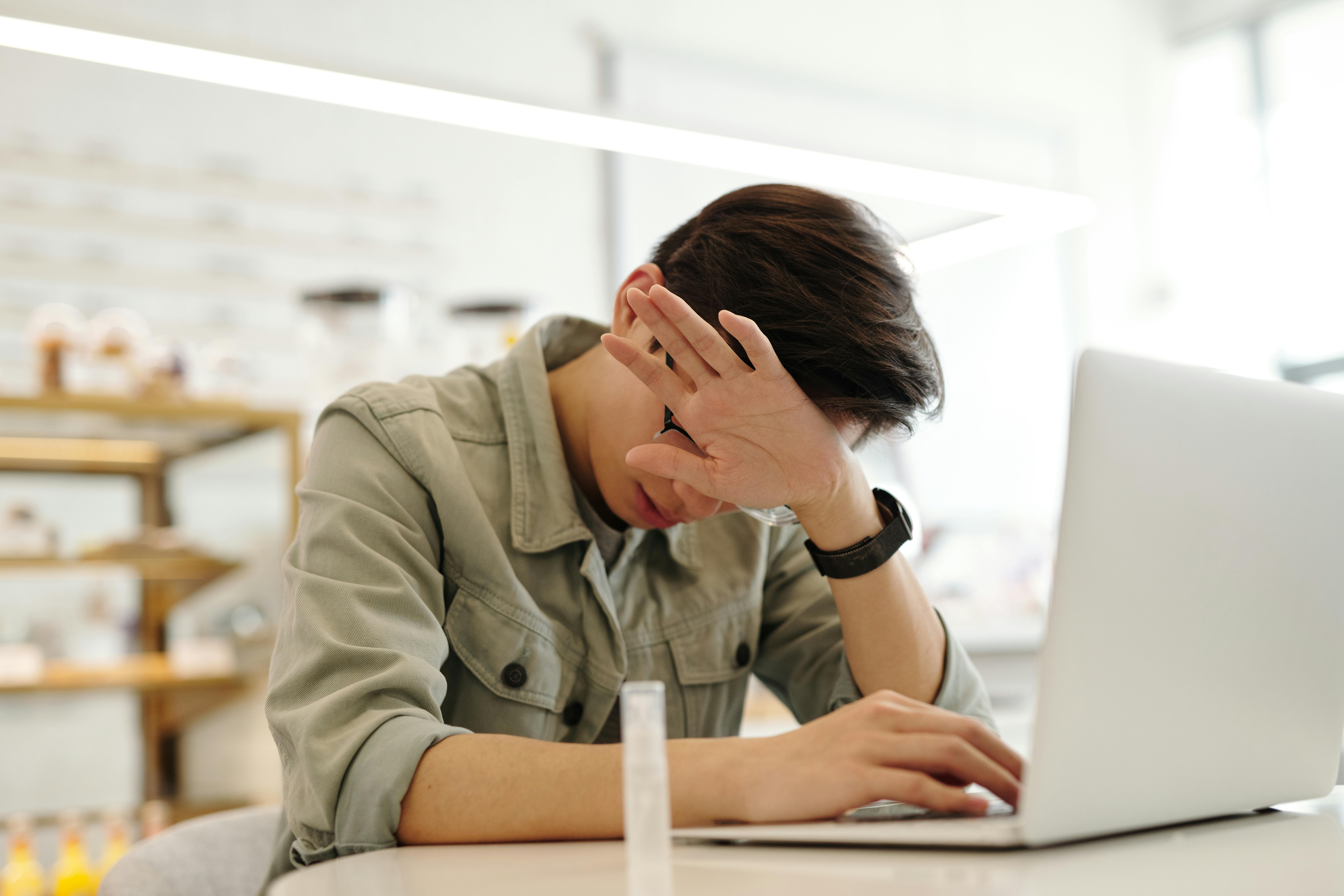 A man working on a laptop in a modern office, feeling the need for better posture.